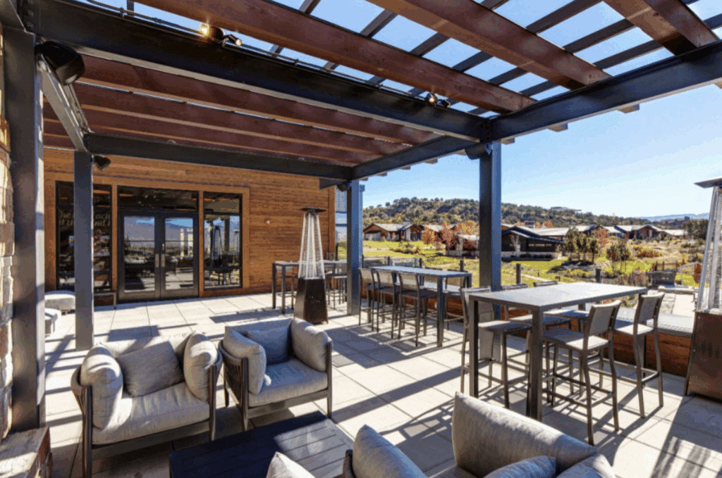 Outdoor patio seating area under wood pergola with sweeping views.